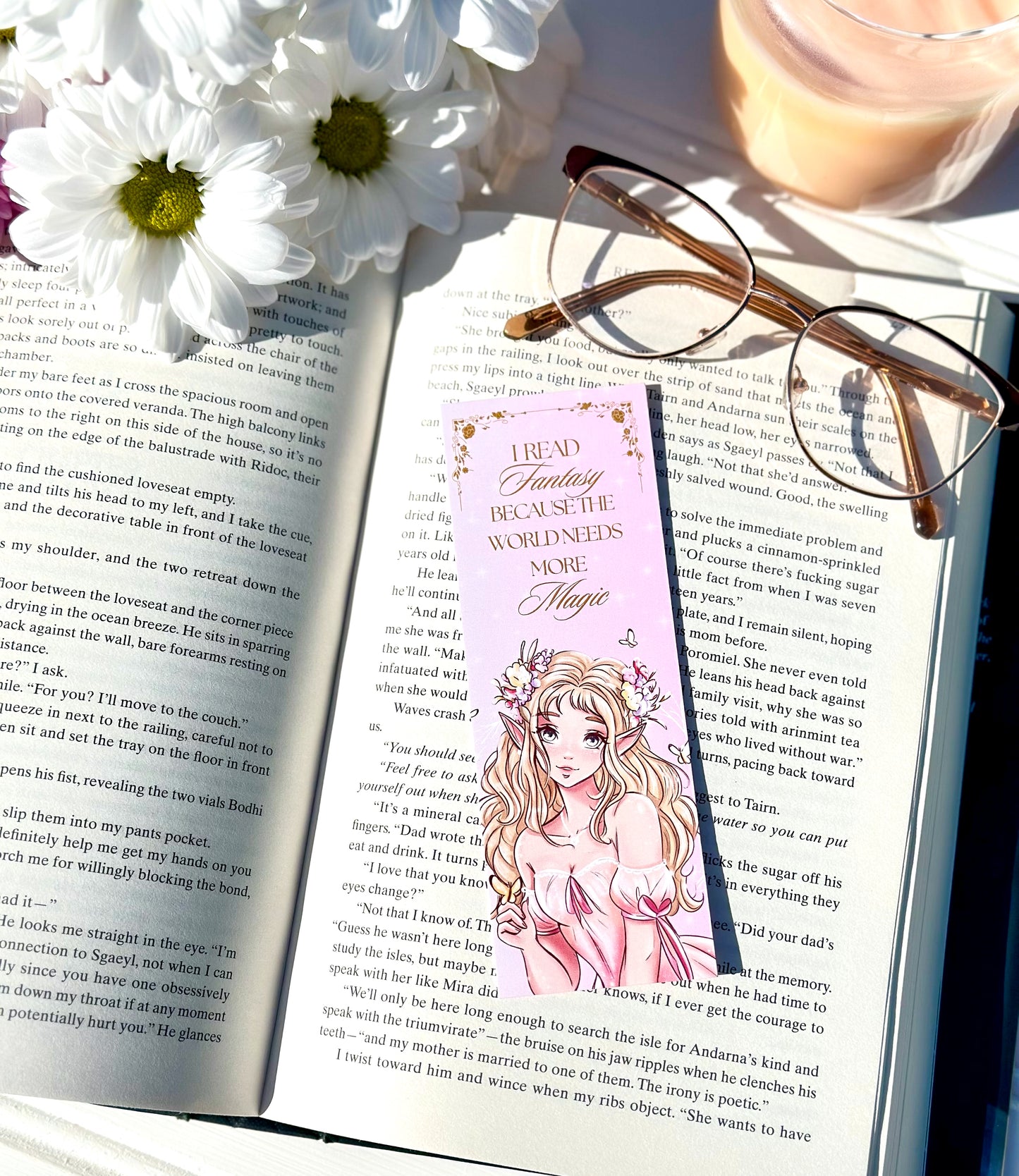 Open book with a pink bookmark featuring an illustration of a fairy princess, glasses, and flowers on a white surface.
