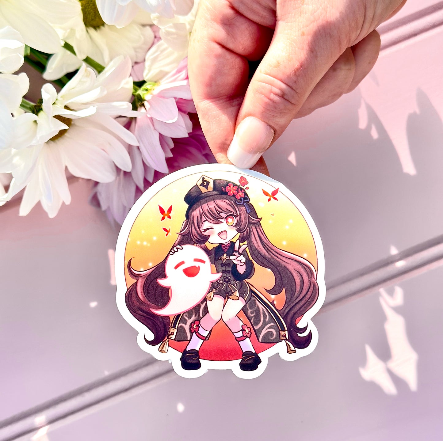 Sticker of a Hu Tao genshin impact character held by a hand with flowers in the background