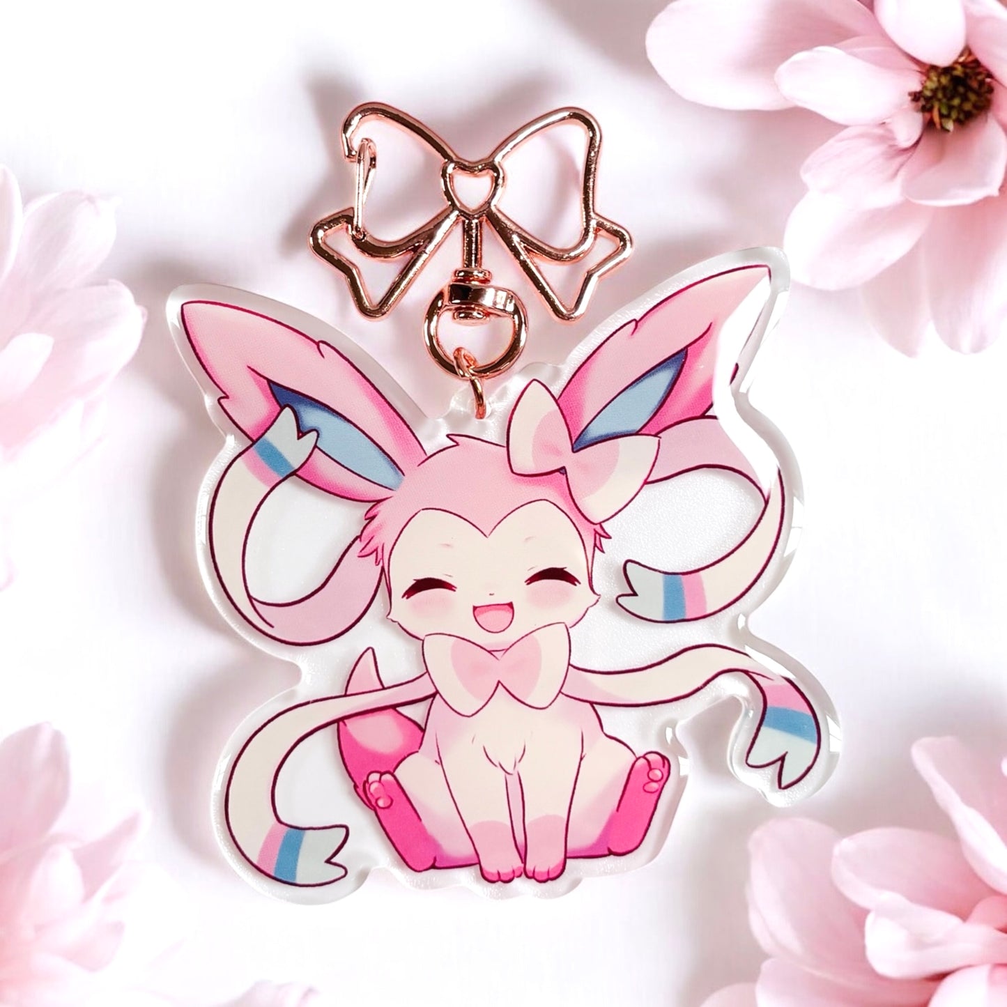 Kawaii sylveon acrylic keychain with metal rose gold clip. cute keychain of sylveon from pokemon. pink aesthetic bag accessory. looking at keychain from a birds eye view