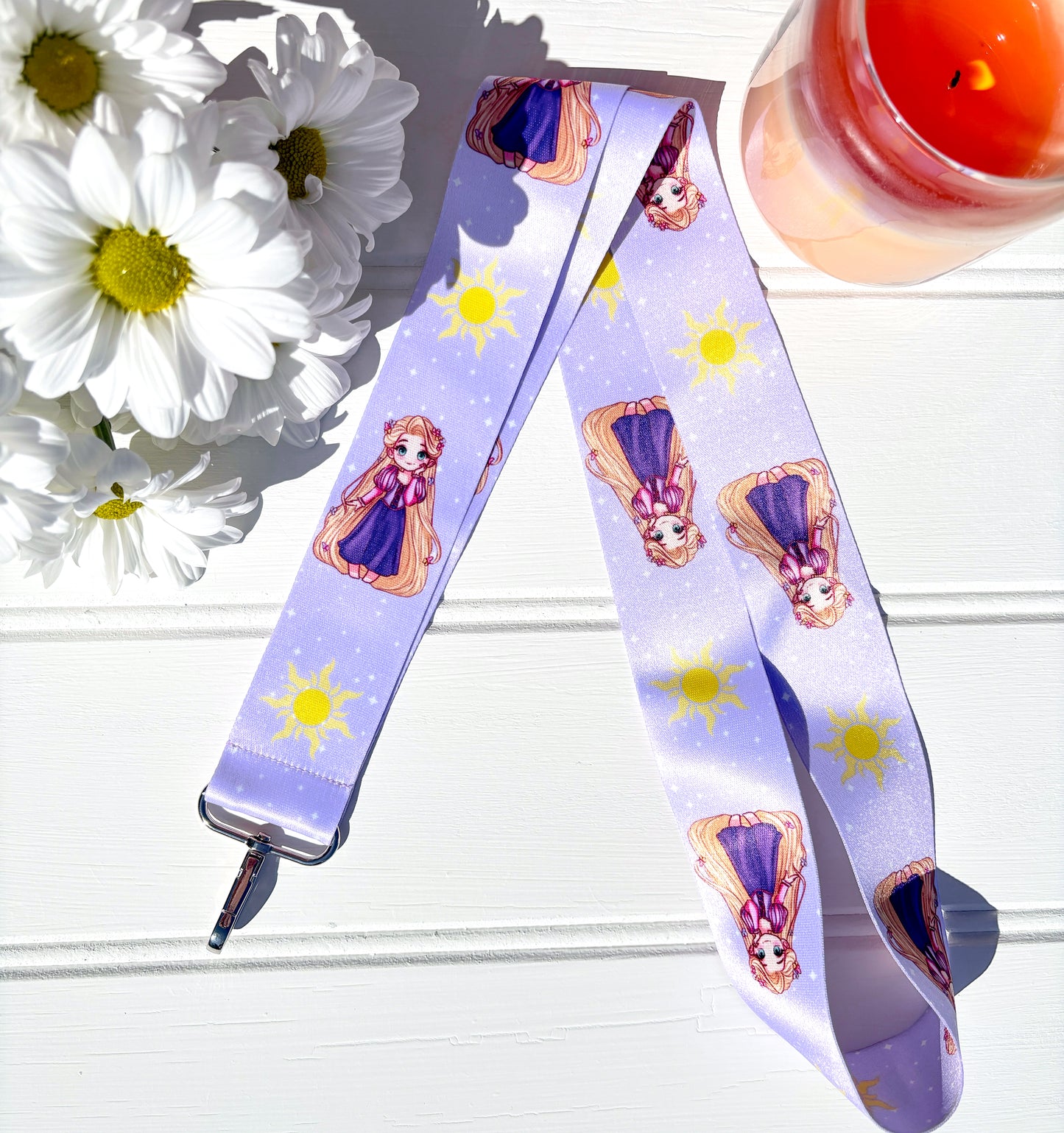 Lanyard with Chibi Rapunzel design on a white surface with flowers and a candle