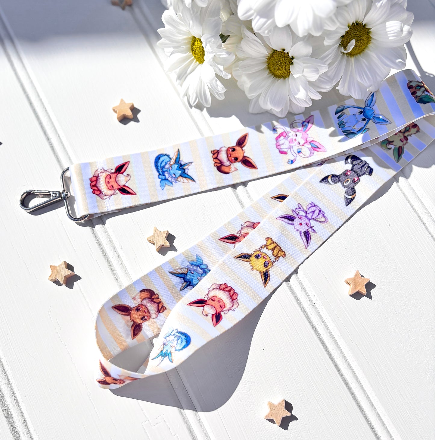Decorative strap with eeeveelutions pokemon characters designs on a white surface with flowers and stars.