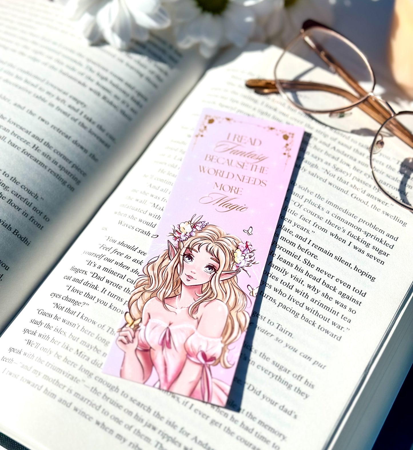 Book with a pink bookmark featuring an illustration of a elf princess with a flower crown, placed on an open book.