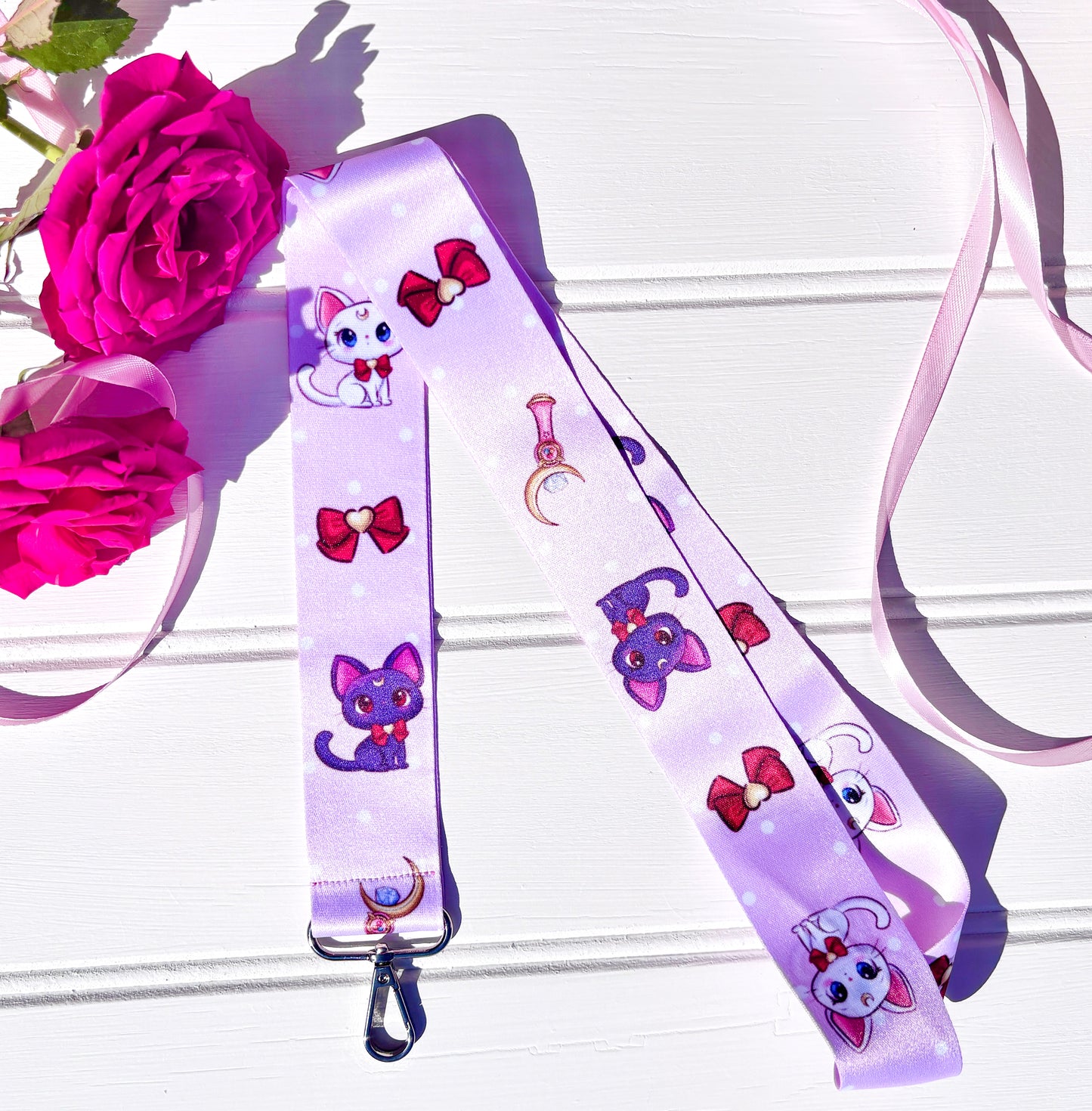 Lanyard with cartoon sailor moon cat designs on a white background with pink flowers