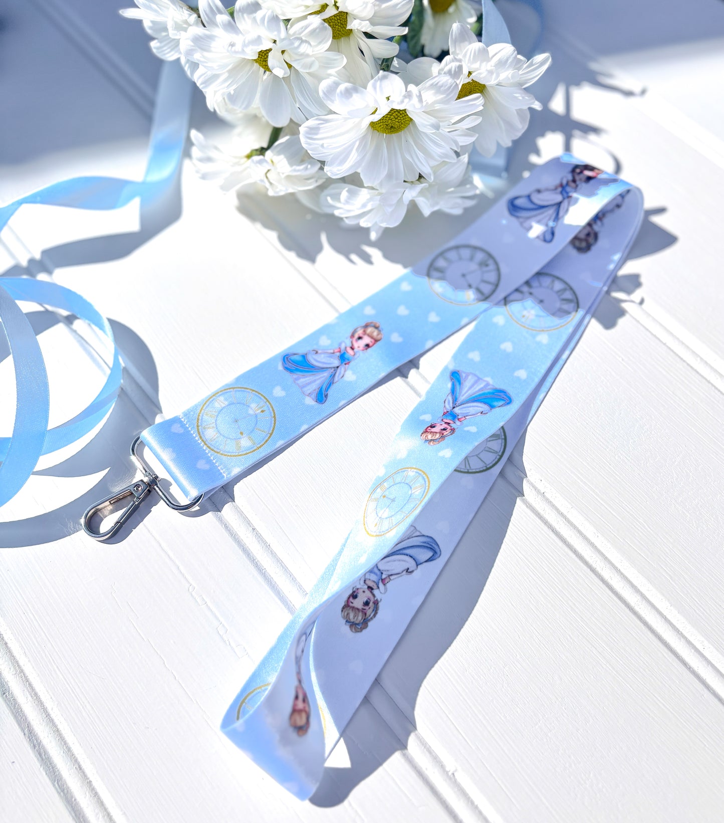Blue lanyard with kawaii cinderella design on a white surface with flowers