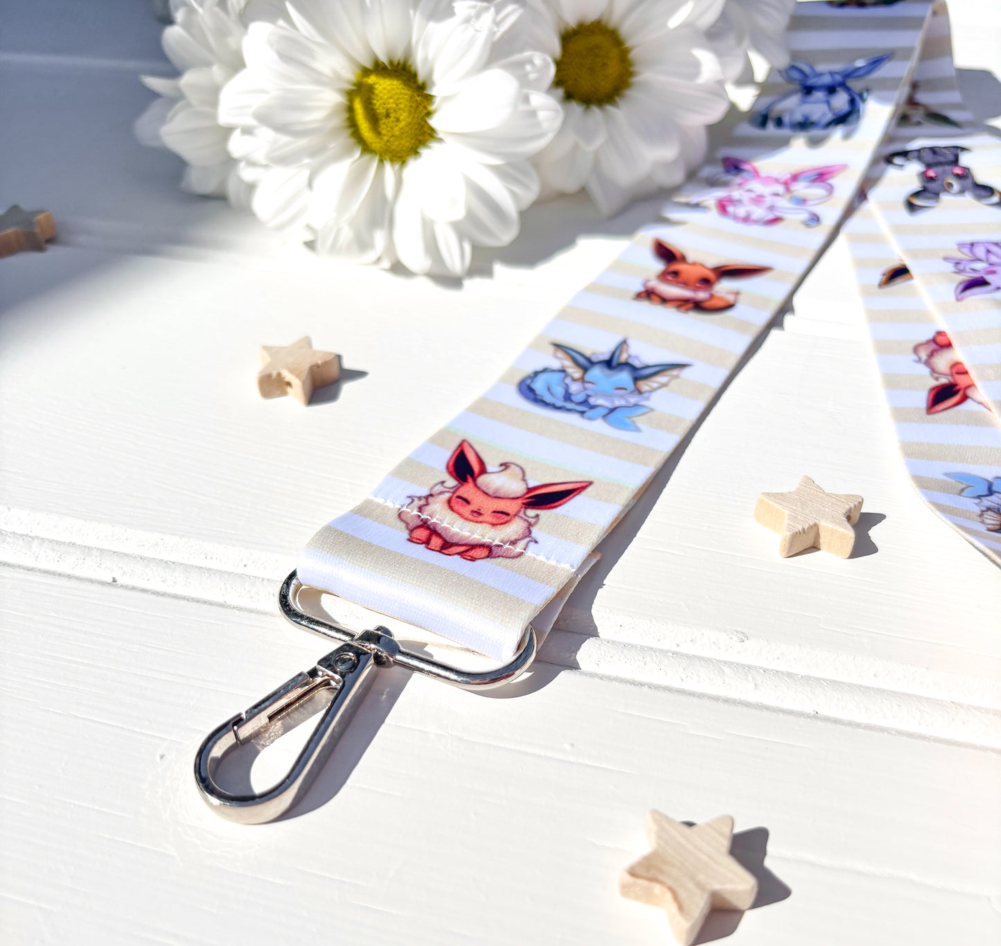 Lanyard with eevee characters on a white surface with flowers and stars
