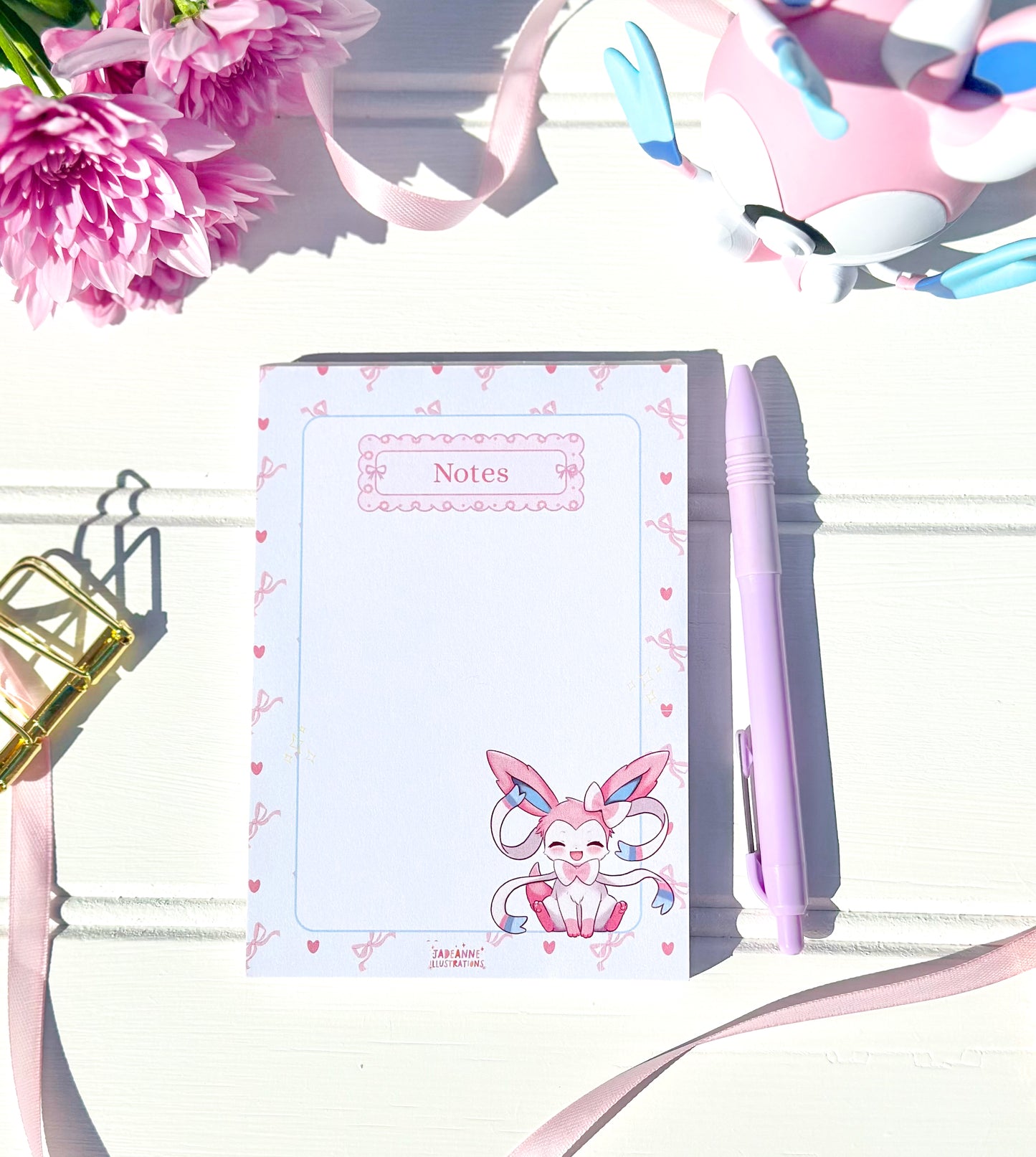 Notebook with kawaii pokemon character design, pen, and flowers on a white background