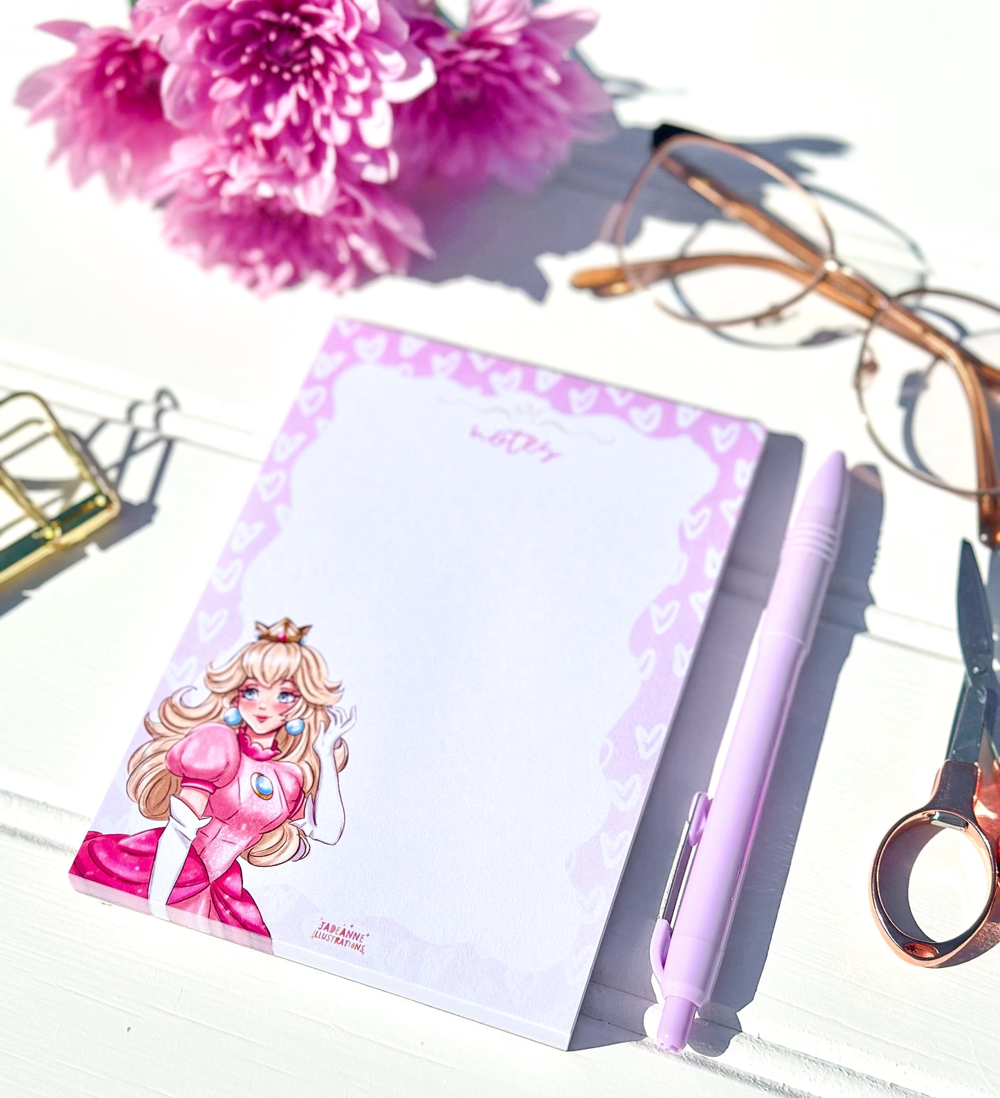 Notebook with a princess character design on a white surface with pink flowers and scissors.