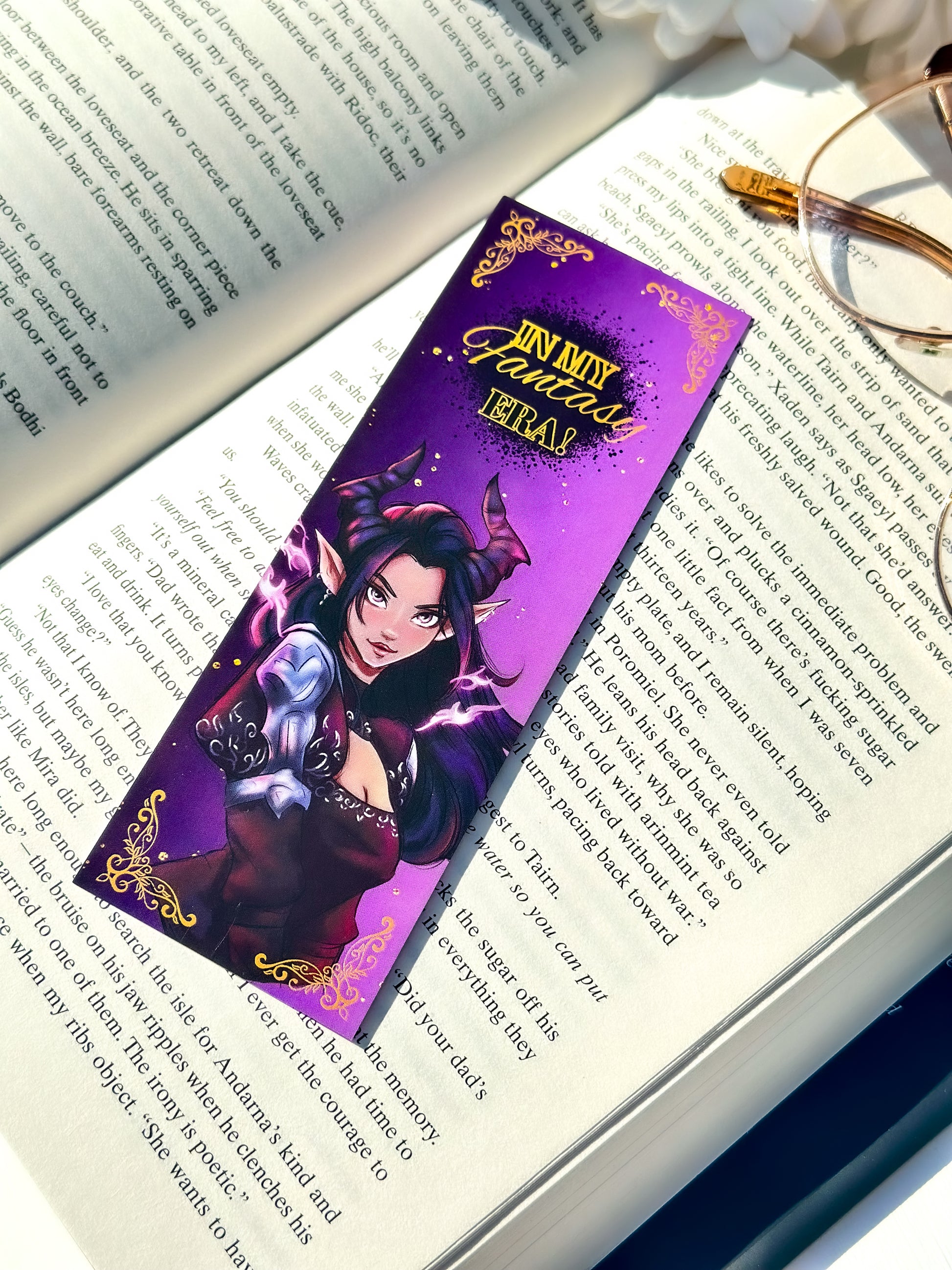 Fantasy-themed dark fae bookmark on an open book with glasses nearby
