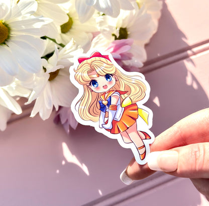 Sticker of Sailor Venus character held by a hand with white flowers in the background