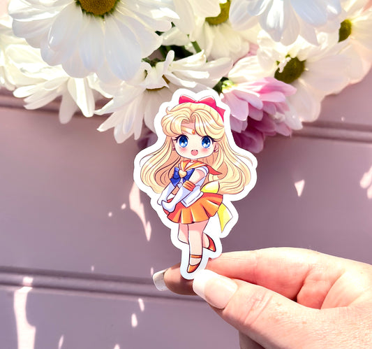 Sticker of a Sailor Venus character held by a hand with flowers in the background