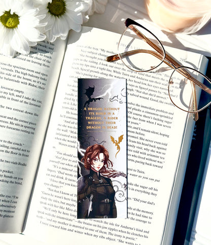 Book with a bookmark featuring an illustration of Violet sorrengail ,glasses, and flowers on an open book.