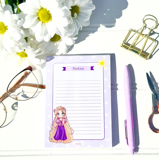 Notepad with Chibi rapunzel character, pen, scissors, glasses, and flowers on a white surface