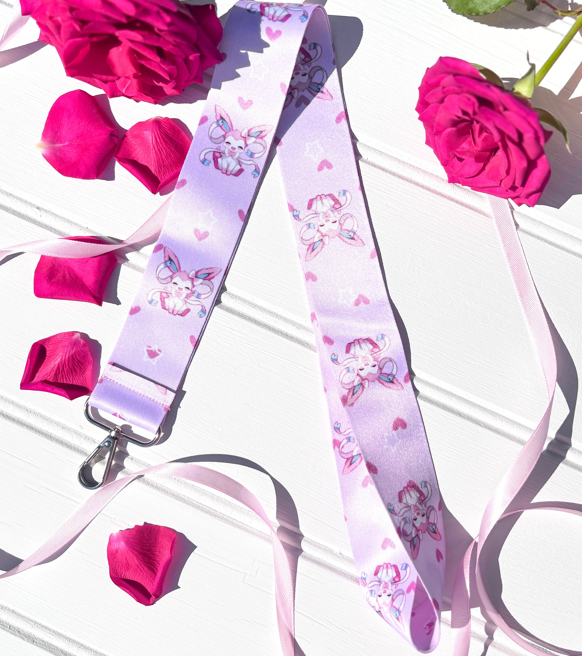 Lanyard with pokemon eeveelution Sylveon character design on a white surface with pink roses and ribbons.