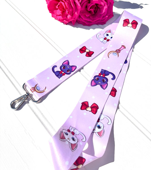Lanyard with sailor moon cartoon characters and bows on a white surface with pink flowers.